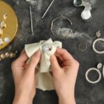 Woman polishing beautiful ring with napkin on grunge background, closeup