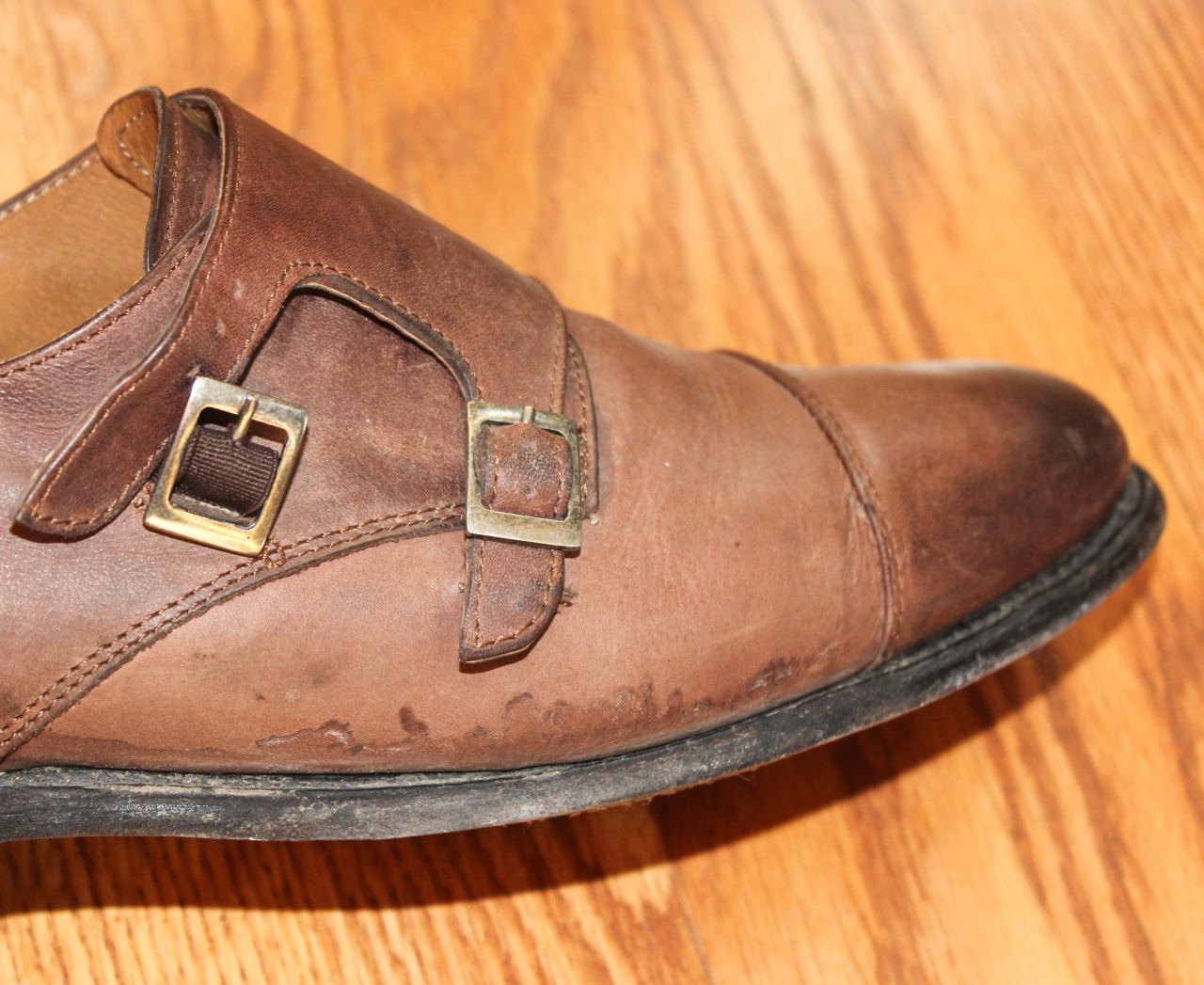 Biała sól osadzona na czarnej skórzanej cholewce buta obok kałuży brudnej wody