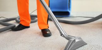 Ekstrakcyjne pranie wykładzin: jak gorąca woda i ciśnienie wyciągają brud, którego odkurzacz nigdy nie ruszy? Pracownik czyści wykładzinę ekstraktorem w domowym salonie z widocznymi zabrudzeniami