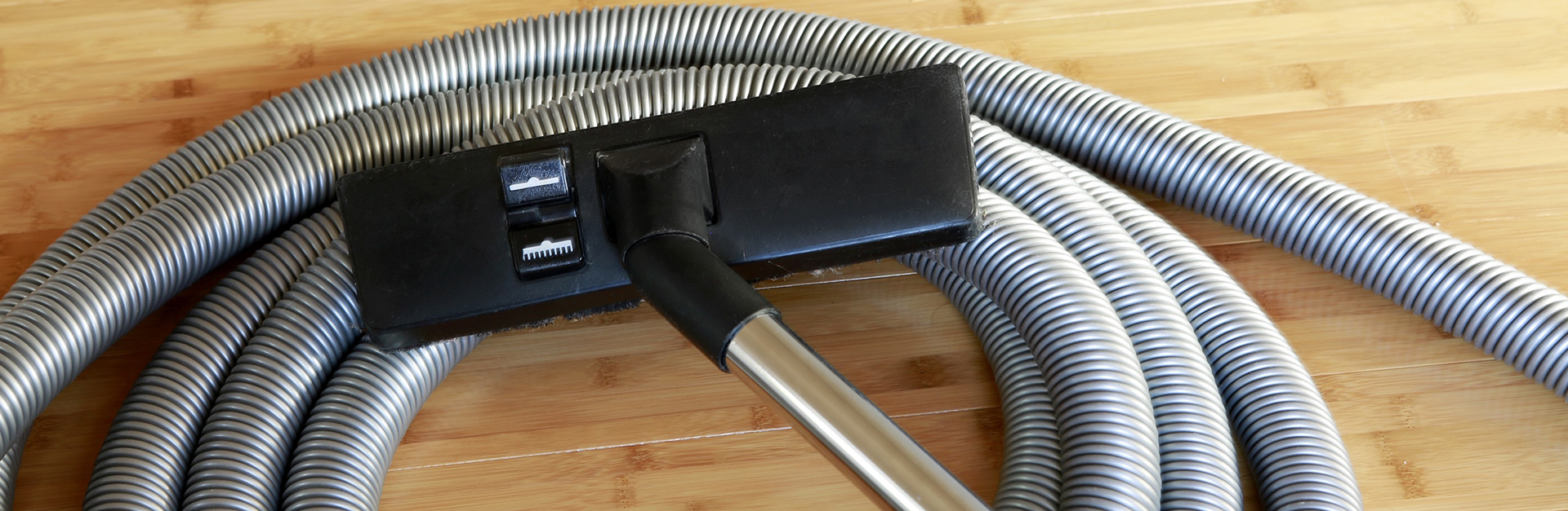 mężczyzna czyszczący schody ssawką odkurzacza centralnego w korytarzu